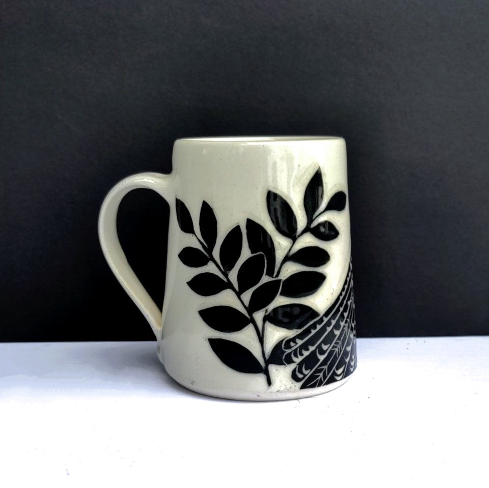 White clay mug with carved black bird and branch design, pottery by Amanda Kerr side view